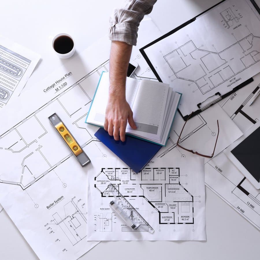 Table d'architecte couverte de plans, de carnets et d'instruments